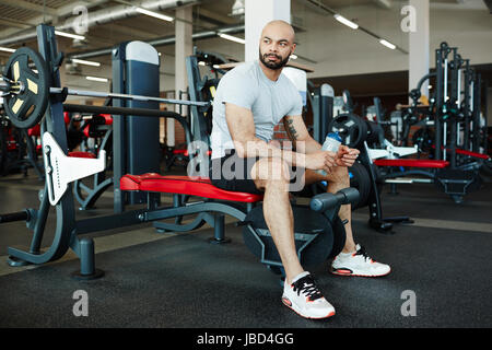 Porträt der schönen muskulösen Sportler sitzen auf Gewichte Bank im modernen Fitnessraum, wegschauen Stockfoto