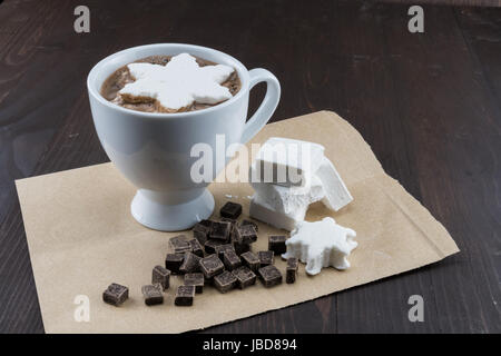 Tasse heiße Schokolade mit Home made Marshmallows und Schokolade-Chips auf braunem Papier Stockfoto