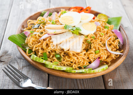 Trocknen Sie Instantnudeln, malaysischen Stil Maggi Goreng Mamak oder würzige trockene Curry-instant-Nudeln. Asiatische Küche, Esstisch aus Holz Einstellung servierfertig. Frisch heiß mit gedünstetem Rauch. Stockfoto