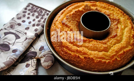 Ein Frisch Gebackener Gugelhupf in der Backform Und Zwei Topflappen A frisch gebacken, Gugelhupf in der Gugelhupfform und zwei Topflappen Stockfoto