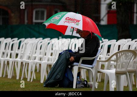 Ein Mann Tierheime vor dem Regen bei einem Cricket-Match unter einem Dach Stockfoto