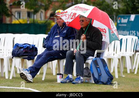 Ein Mann Tierheime vor dem Regen bei einem Cricket-Match unter einem Dach Stockfoto