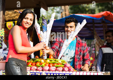 Lächelnd Teenager Boy geben Bhelpuri Mädchen Stall Messe in Surajkund Stockfoto