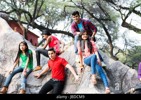 Glückliche Gruppe Teenager Jungen Mädchen Freunde sitzen Rock genießen Surajkund Stockfoto