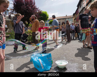 Ein Showman macht und bläst massive Bläschen zur Unterhaltung der Kinder an einem Wochenende fair in Mirepoix, Languedoc, Frankreich Stockfoto