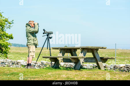 Ottenby, Schweden - 27. Mai 2017: Ökologische Dokumentarfilm. Männliche Vogelbeobachter Blick über die Landschaft mit dem Fernglas. Spotting Scope stehende o Stockfoto