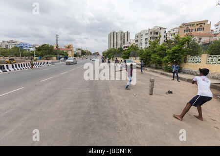 Indische Kinder Kricket spielen auf einer belebten Straße in Hyderabad, Indien. Stockfoto