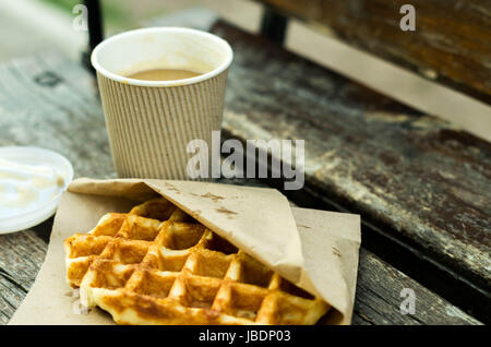 Glas Kaffee und eine belgische Waffel auf einer Bank. Stockfoto