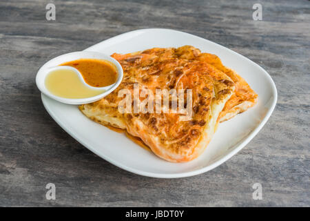 Indische Roti Prata mit Kondensmilch und Curry-Sauce, Nahaufnahme von rustikalen indischen Roti gebratenen Pfannkuchen Stockfoto