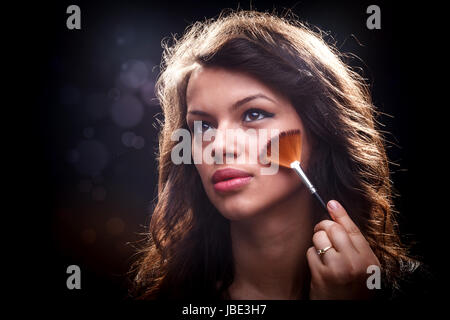 Junge Frau entfernen überschüssige Pulver mit Fächerpinsel Stockfoto
