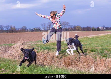 Junge Frau Springt Mit Hunden Über Einen Graben Stockfoto