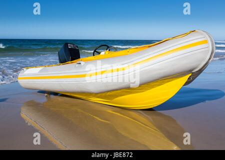 Gelbe und weiße Ente aufblasbar Schlauchboot am Sandstrand Stockfoto