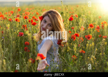 Schöne junge Frau im Mohnfeld Blick in die Kamera Stockfoto