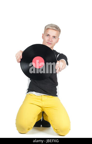 Junger Mann aus Vinyl-Platte zeigt und auf dem Boden sitzend Stockfoto