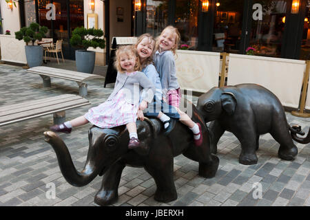 Kinder, Kinder, Mädchen, Fahrt und spielen auf die Skulptur die drei Grazien, von Philippa Downes, die Skulpturen Thema 3 Elefanten. Leamington Spa. UK Stockfoto