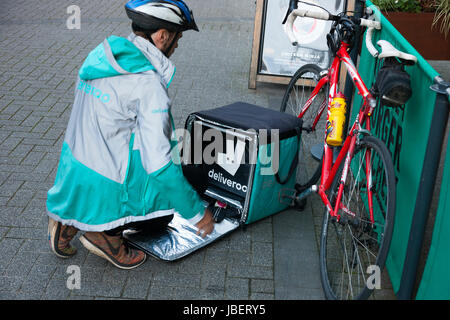 Deliveroo Speisen zum Mitnehmen Kurier Pedal Lieferzyklus / Push Fahrrad Radfahrer machen eine Lieferung laufen in Royal Leamington Spa. GROßBRITANNIEN (88) Stockfoto