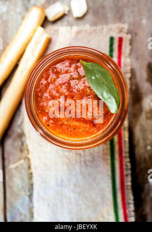 Grissini-Brot-sticks mit einem Glas von herzhaften würzigen Tomaten-Relish für eine leckere italienische Vorspeise, Draufsicht mit Exemplar Stockfoto