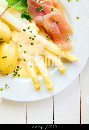 Köstliches kaltes Abendessen von Spargel und Schinken Schinken serviert mit Mayonnaise und Baby Salzkartoffeln garniert mit frischen gehackten Kräutern, Draufsicht auf einem weißen Teller und Tisch hautnah Stockfoto