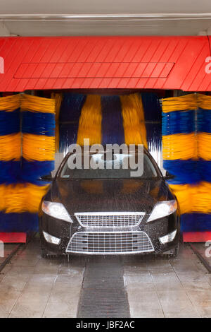 Auto gewaschen in automatische Waschanlage, drehen, blau und gelb Pinsel sichtbar; unrecognizible Fabrikat und Modell Etiketten, Model-Release wird nicht benötigt. Stockfoto