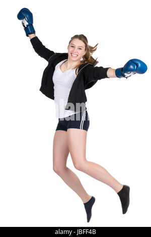 Freigestelltes Foto Einer Jungen Lächelden Boxerin Im Kapuzenpulli Und Mit Blauen Boxhandschuhen, sterben in Die Luft springt Stockfoto