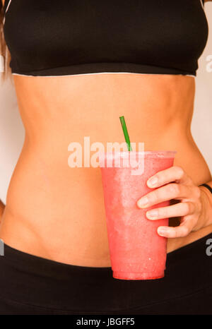 Frau hält grüne Frucht Smoothie Taille Ebene zeigt gesunden schlanken Körper Stockfoto