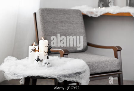 Graue Polsterstuhl in Halloween Ambiente mit Kerzen Stockfoto