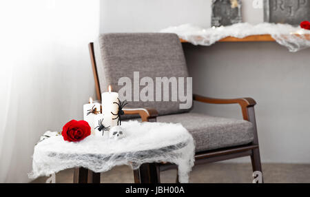 Graue Polsterstuhl in Halloween Ambiente mit Kerzen Stockfoto