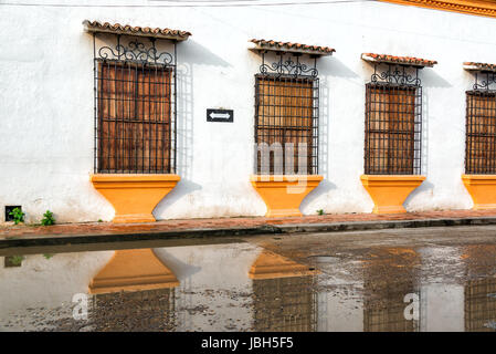 Windows auf einer kolonialen Wand spiegelt sich im Wasser auf dem Boden in Mompox, Kolumbien Stockfoto