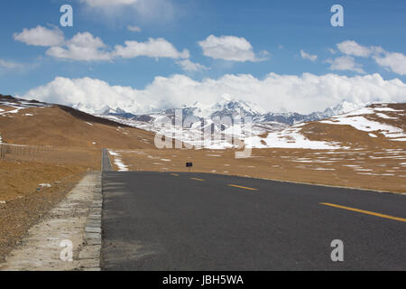 Gerade Straße mit einer gelben gepunkteten Linie in der Mitte mit tibetischen Landschaft der Berge im Hintergrund. Friendship Highway in Tibet. China 2013. Stockfoto