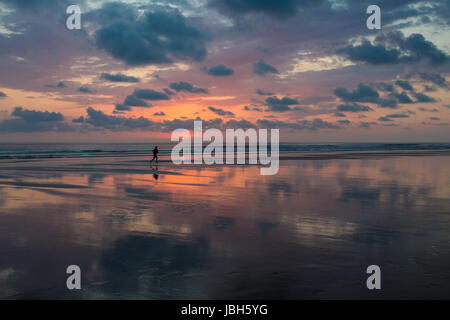 Blick auf den Sonnenuntergang am Strand von Matapalo mit Silhouette der Mann, der seine Joggen, Costa Rica. Matapalo liegt in der südlichen Pazifikküste. Die Hauptattraktionen sind Surfen und Öko-Tourismus, Costa Rica 2013. Stockfoto