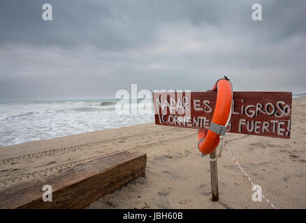 Rettungsring und Zeichen auf Spanisch, die besagt, dass es gefährlich ist, Schwimmen in Palomino, Kolumbien. Stockfoto