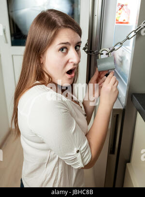 Porträt von Brünette Frau, die versucht, die Sperre auf Kühlschrank öffnen Stockfoto