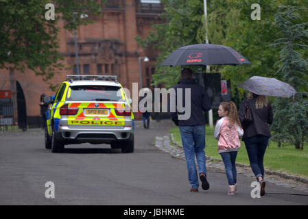 Glasgow, Schottland. 11. Juni. Die beiden Elemente der in diesem Jahre britische Sommer waren anwesend, als Regen auf die West End Festival Big Sunday im Kelvingrove Park strömte. Besucher wurden stark durch die Polizei und private Sicherheitsdienste überwacht. Bewaffnete Polizei patrouilliert Parks im Fahrzeuginneren während Taschen durch private Sicherheitspersonal an den Eingängen durchsucht wurden.  Polizisten patrouillierten Veranstaltungsort zu Fuß oder Fahrrad.  Kredit Gerard Fähre/Alamy Live-Nachrichten Stockfoto