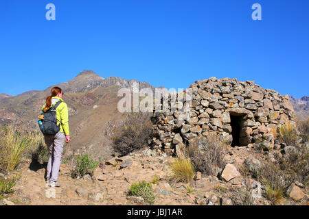 Touristen auf der Suche im Pre-Inka-Runde House benannt Colca in der Nähe von Chivay in Peru. Colcas sind kreisförmige Stein-Strukturen für die Lagerung von Lebensmitteln oder Bestattungen verwendet. Stockfoto