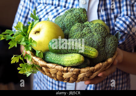Person (Hände) halten Korb mit Bio-grüne Gemüse (Brokkoli, Gurken, Apfel und Petersilie) - gesunde Bio Detox Diät Vegan vegetarisch roh ea Stockfoto