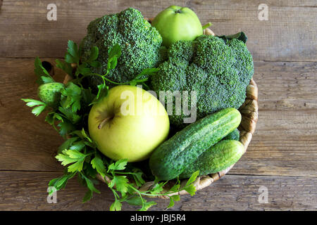 Gemüse. Sortierte Bio Ernte grünes Gemüse in einem Korb. Frisches Gemüse über rustikalen hölzernen Hintergrund. Stockfoto