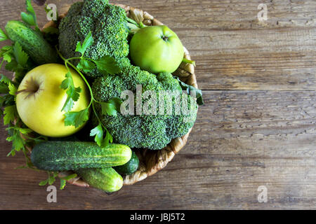 Gemüse. Sortierte Bio Ernte grünes Gemüse in einem Korb. Frisches Gemüse über rustikalen hölzernen Hintergrund. Stockfoto