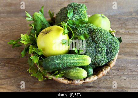 Gemüse. Sortierte Bio Ernte grünes Gemüse in einem Korb. Frisches Gemüse über rustikalen hölzernen Hintergrund. Stockfoto