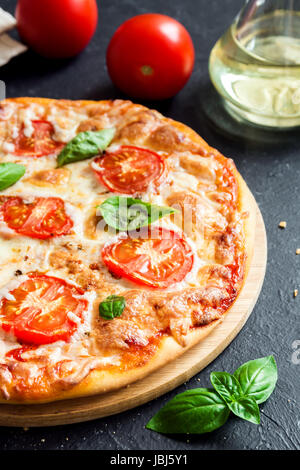 Pizza Margherita auf schwarzem Stein. Hausgemachte Pizza Margarita mit Tomaten, Basilikum und Mozzarella-Käse. Stockfoto