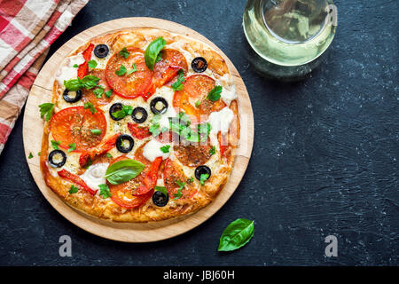 Italienische Pizza mit Tomaten, Salami, schwarzen Oliven und Mozzarella-Käse, Ansicht von oben. Frische hausgemachte Pizza. Stockfoto