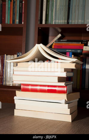 Bücher über Holztisch mit Bücherregalen auf der Rückseite Stockfoto
