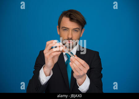 Geschäftsmann Nachfüllen seine e-Zigarette mit e-Liquid auf blauem Hintergrund Stockfoto