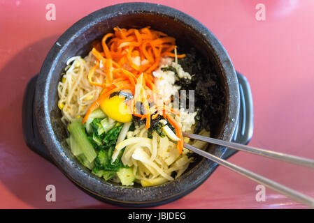 Bibimbap in einem beheizten Stein Schüssel, ein koreanisches Gericht mit Ei und frischem Gemüse Stockfoto