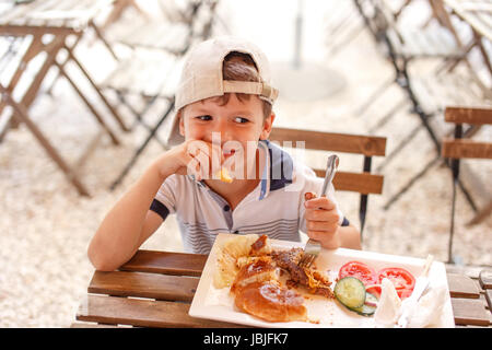 Kleinen kaukasischen jungen in GAP Straße Essen im restaurant Stockfoto