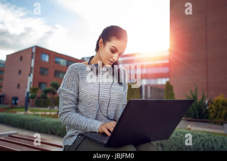 Frau, die Eingabe auf Laptop im Freien im Stadtpark, wireless-Technologie Stockfoto