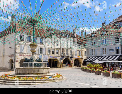 Springbrunnen und die umliegenden Gebäude in Place De La Liberté, geschmückt für eine Fête, Arbois, Jura, Frankreich Stockfoto