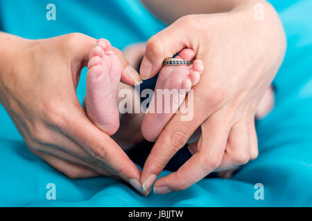 Mutters Hände bilden einen Herd um Baby Füße. Stockfoto