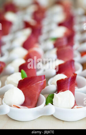 Nahaufnahme von Schinken und Kugel geformt Mozzarella Käse Häppchen in Reihen von kleinen weißen mit Gerichten und Zeile der Brotscheiben Stockfoto