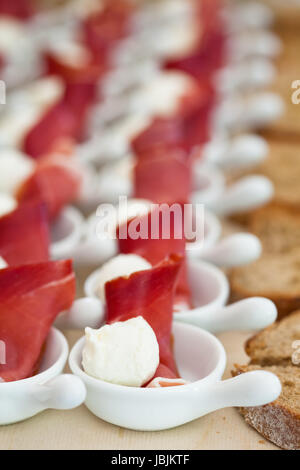 Nahaufnahme von Schinken und Kugel geformt Mozzarella Käse Häppchen in Reihen von kleinen weißen mit Gerichten und Zeile der Brotscheiben Stockfoto