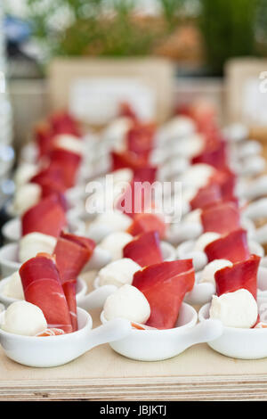 Nahaufnahme von Schinken und Kugel geformt Mozzarella Käse Häppchen in Reihen von kleinen weißen Schüsseln Stockfoto